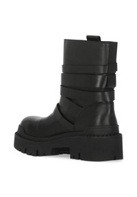 Stivaletto alla caviglia in pelle nera con design a strati, suola spessa e linguetta laterale per tirare. Presenta una texture liscia e un tacco a blocco con fondo scolpito.