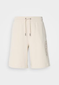 Beige, cotton blend shorts with a drawstring waistband, side pockets, and embroidered "Calvin Klein" logo on the left leg.
