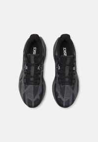 Baskets noires de sport avec une tige texturée présentant un motif géométrique. Design à lacets avec une semelle intérieure rembourrée et une semelle extérieure en caoutchouc.