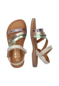 Platte sandalen met gevlochten metalen banden in goud, zilver en mintgroen op een tan leren zool; gestructureerd wit accent voor contrast.