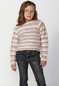 Pull rayé multicolore en maille douce, avec des teintes pastel de rose, crème et violet. Associé à un jean en denim foncé.