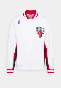 Hvid bomberjakke med røde og sorte detaljer, prydet med "Chicago Bulls" logo og NBA-emblem på venstre skulder. Rødsstribede mansjetter.