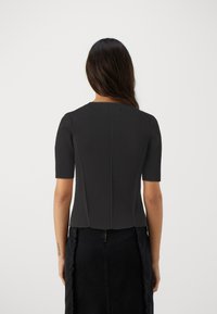 Black fitted top with short sleeves, structured design, and smooth texture, featuring a back seam and a rounded neckline.