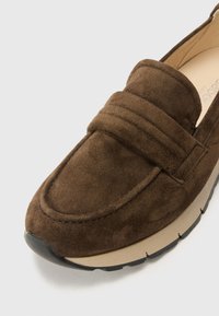 Brown suede moccasin shoe with a stitched toe cap, a padded instep, and a solid rubber outsole in black. Smooth interior lining.