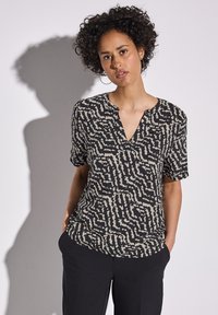 Schwarzes T-Shirt mit kurzen Ärmeln und einem abstrakten Muster in Creme und Beige, mit V-Ausschnitt und lockerer Passform, aus leichtem Stoff gefertigt.