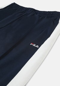 Himmelblau Sweatpants mit elastischem Bund, weißen Seitenstreifen und einem kleinen, rot-weiß gestickten Fila-Logo. Glatte Stoffstruktur.