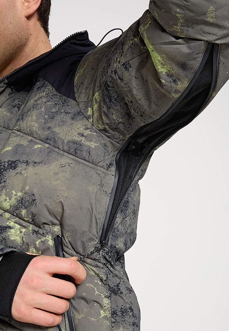 Doudoune en vert et gris, avec une texture matelassée, des zips sur les côtés et une doublure en mesh pour la ventilation.