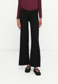 Svart randig byxa med vida ben och hög midja, med en texturerad design. Matchas med svarta prydnadsballerinas för kontrast.