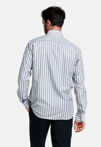 Gestreept shirt in lichtblauw en wit, met lange mouwen en een knoopsluiting bij de manchetten. Heeft een gestructureerde kraag en een afgeronde zoom.