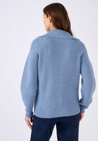 Suéter de punto azul claro con un patrón texturizado, mangas amplias y un dobladillo y cuello acanalados.