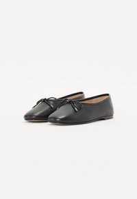 Ballerines en cuir noir avec des orteils ronds, des lacets fins et une semelle plate. Texture lisse avec un minimum de matériel et sans motifs visibles.