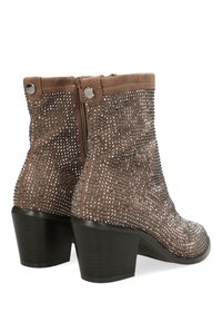 Botas de tobillo de ante marrón con una superficie texturizada, adornadas con tachuelas plateadas, con un tacón grueso y un cierre de cremallera en el costado.