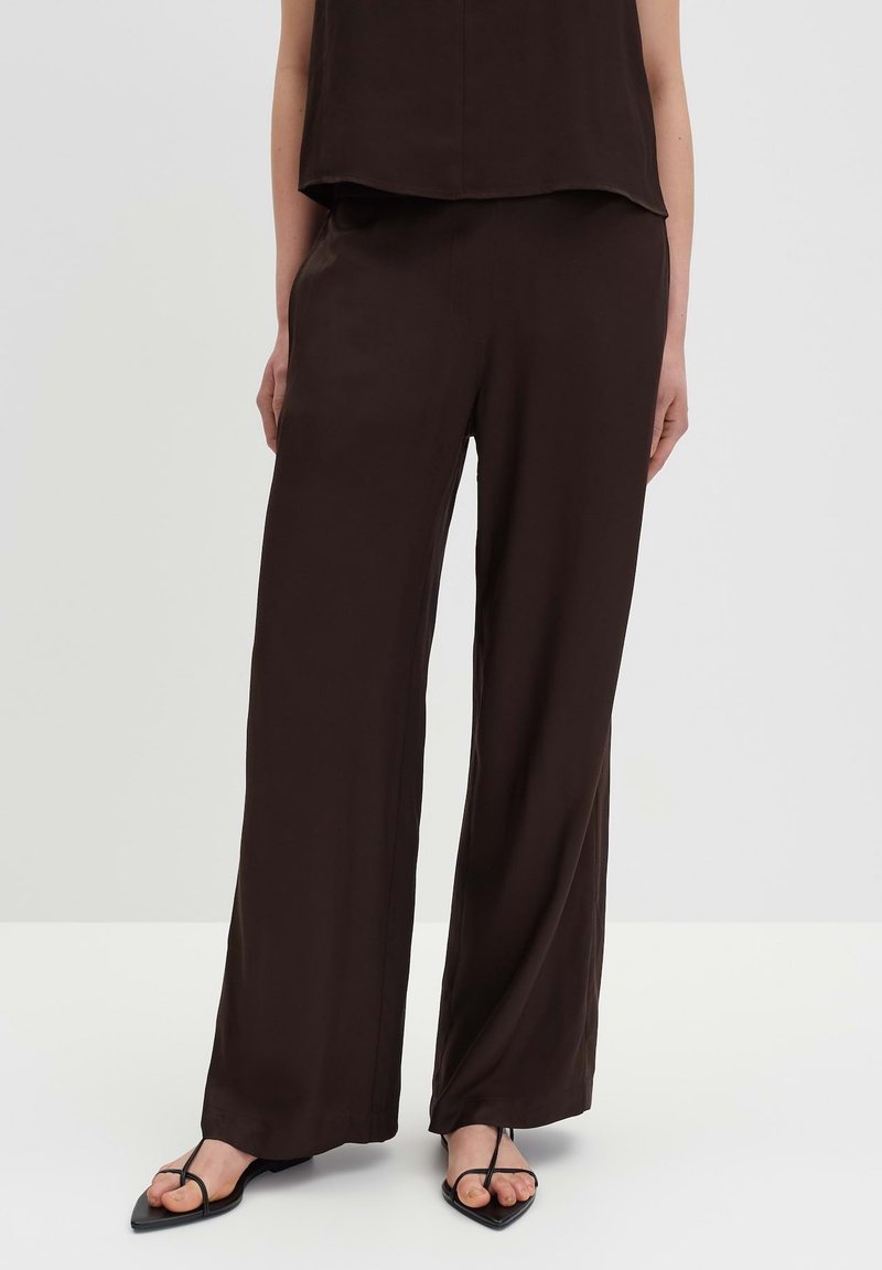 Brown, loose-fitting trousers made from a smooth fabric; features a wide leg design with a simple, unembellished look.
