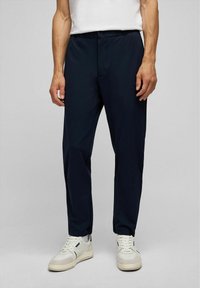Marineblauwe broek van een lichtgewicht, glad materiaal. Elastische tailleband met een knoopsluiting, taps toelopend ontwerp van de benen en zijzakken.