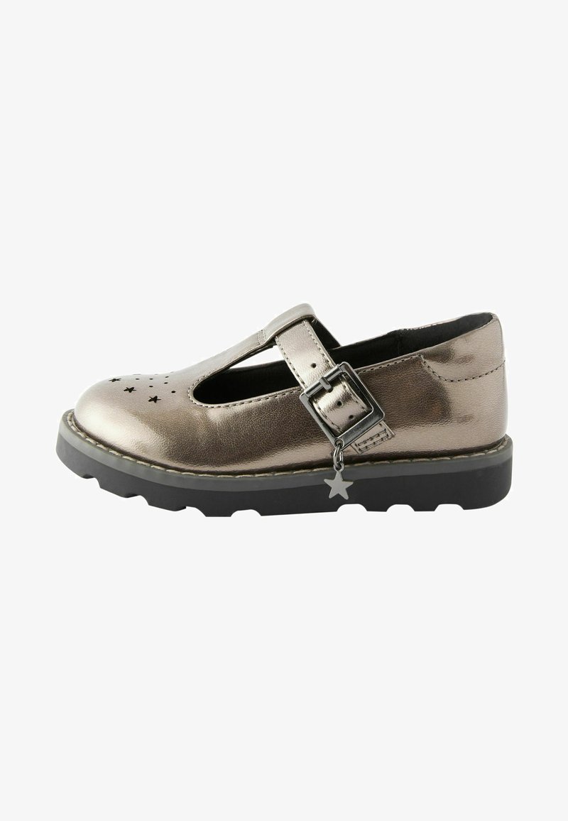 Chaussure T-bar en métal argenté avec un design étoile perforé, une sangle à boucle, une semelle en caoutchouc noir et un détail en forme d'étoile. Plat avec un bout arrondi.
