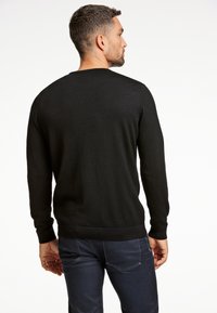 Czarny dzianinowy sweter z długimi rękawami i okrągłym dekoltem, o gładkiej fakturze i ściągaczach na rękawach, widoczny z tyłu.