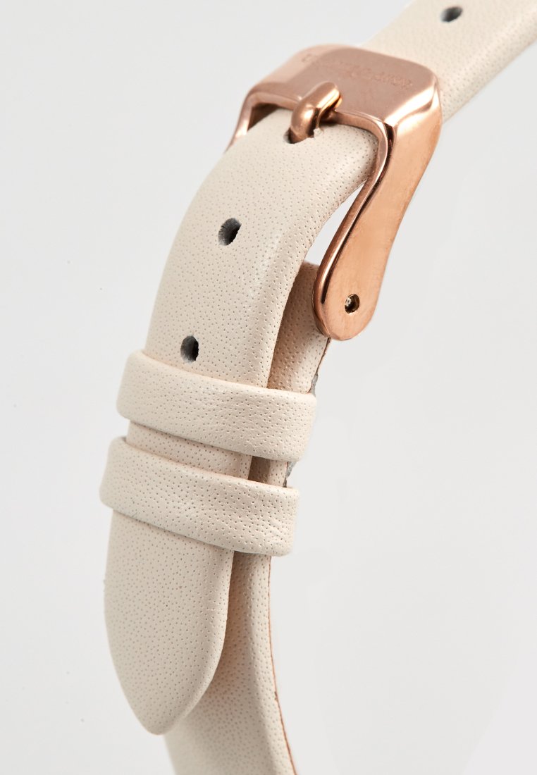 Correa de reloj de cuero beige con una superficie texturizada, equipada con una hebilla de metal en color oro rosa y múltiples orificios de ajuste.