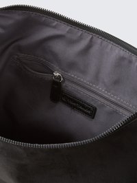 Černá semišová taštička s vnitřkem, který obsahuje zipovou kapsu a hladkou podšívku, se šitím a nenápadnou značkovou etiketou.