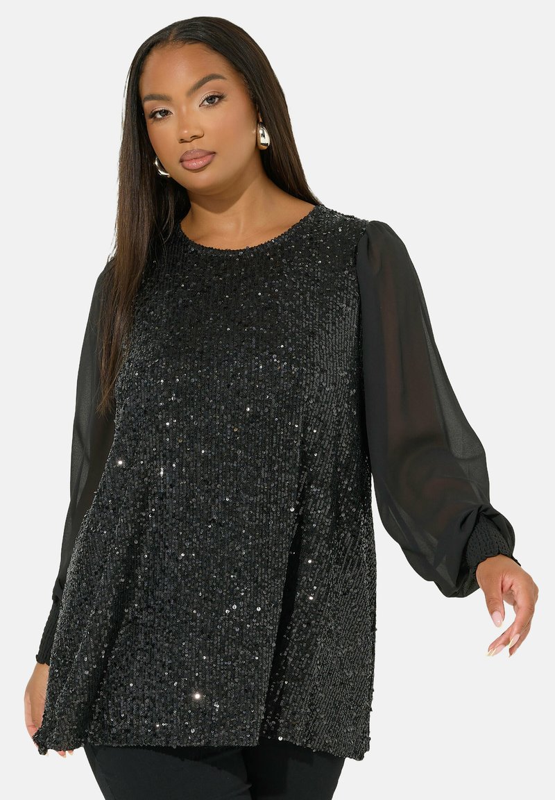 Svart paljett-topp med långa genomskinliga puffärmar, rund halslinning och rak skärning. Den glansiga ytan har olika reflekterande paljetter.