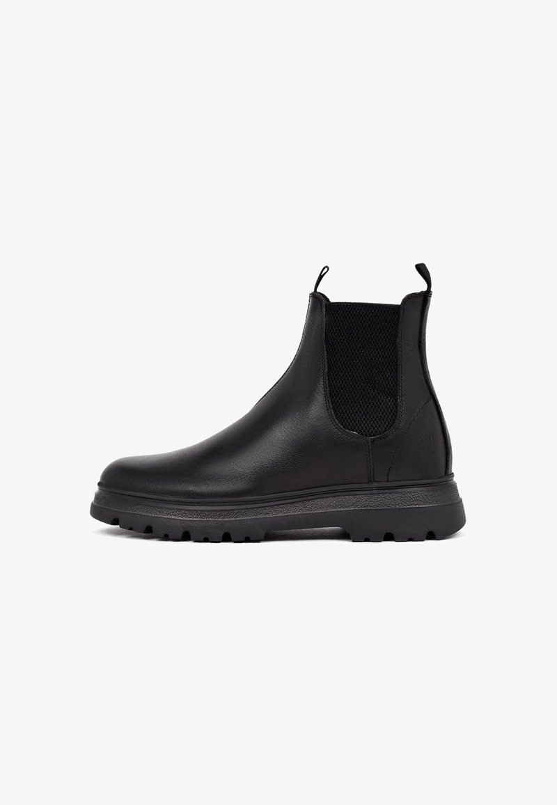 Botas Chelsea de cuero negro con paneles laterales elásticos, suela de goma texturizada, lengüetas en el talón y un diseño elegante para un uso fácil.