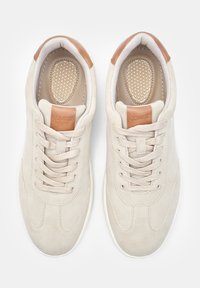 Beežid nubukist spordijalatsid sujuva viimistlusega, millel on pruuni nahast aksent kanna piirkonnas ja tekstureeritud sisetald, shoelace disain ja ümarast toe.