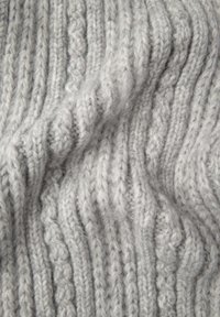 Grå strikket stof med et tykt, struktureret mønster, der har skiftevis ribbede og snoede designs, som fremhæver bløde, fluffy fibre.