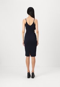Tamno plavi bodycon haljina s podesivim tankim trakama, izrezima sa strane i prorezom na leđima. Napravljena od glatkog, rastezljivog materijala.