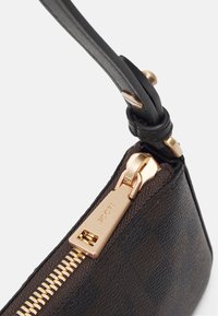 Svart läder axelväska med texturerad yta, med en guldfärgad dragkedja och hårdvara, samt ett slätt svart band. Etiketten läser "JOOP!"