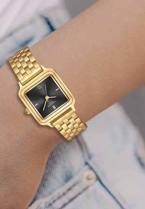 Montre en métal doré avec un cadran noir rectangulaire, comportant des marqueurs d'heure, deux aiguilles et un bracelet en style tressé.