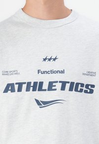 Graues Baumwoll-T-Shirt mit navyblauer Aufschrift "ATHLETICS" und Grafiken. Rundhalsausschnitt, kurze Ärmel und bedruckte Slogans.