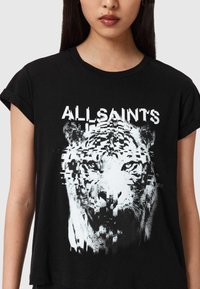 Tricou grafic negru cu un imprimeu distorsionat de tigru alb și text "ALL SAINTS" într-un font modern pe față. Mâneci scurte, croială lejeră.