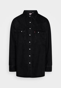 Mustat farkkukangashuppari, jossa on terävä kaulus, nepparilla suljettava etuosa, kaksi rintataskua ja kontrastiväriset valkoiset napit. Ominaisuutena jämäkkä rakenne.