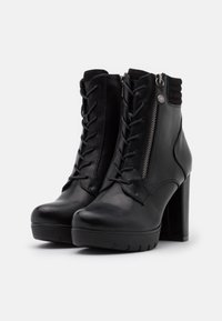 Bottes chevilles en cuir noir avec un talon bloc haut, dotées d'un laçage avant, d'une fermeture éclair latérale et d'un tissu texturé au col.