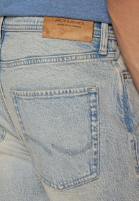 Lyseblå denimjeans med teksturert finish, med et lærmerke som har "JACK & JONES JEANS INTELLIGENCE" og detaljer i baklommens søm.