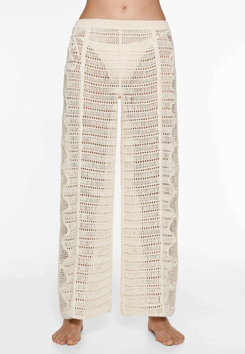 Pantalons large à taille haute de style crochet en crème, dotés d'un tissage ouvert avec des motifs verticaux et ondulés sur les côtés.