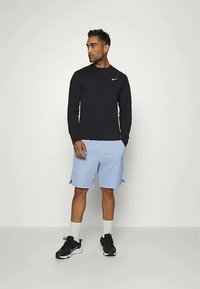 Black long-sleeve shirt with a small white logo, light blue shorts, black sneakers, and white socks. Simple, athletic design.