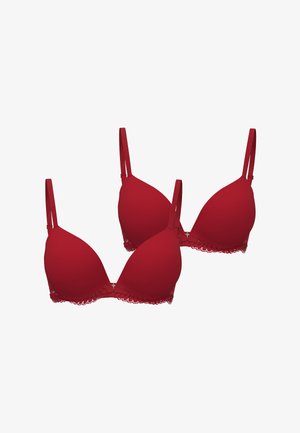 Red bras with padded, seamless cups and adjustable straps. Lace trim along the bottom adds detail. Two pieces are displayed together.