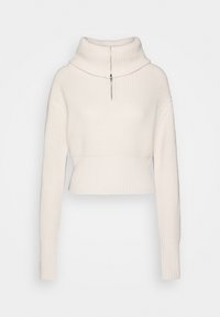 Gekürzter Cremepullover mit gerippter Textur, hohem Kragen und halbem Reißverschluss. Verfügt über lange Ärmel und einen taillierten Bund.