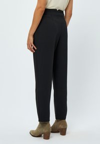 Pantaloni a vita alta di colore grigio scuro con gamba dritta, abbinati a stivaletti taupe con tacco impilato. Tessuto dalla superficie liscia.