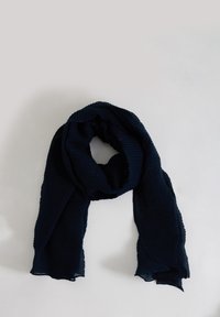 Bufanda azul marino hecha de tela ligera y texturizada con pliegues sutiles y una forma suave y fluida. Los bordes están ligeramente deshilachados.