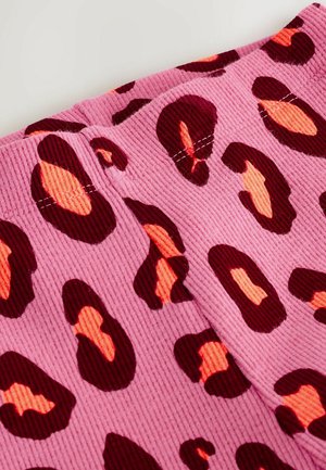 Tela de pana rosa con manchas de leopardo en rojo oscuro y naranja, con detalles de costura visibles y una superficie texturizada.
