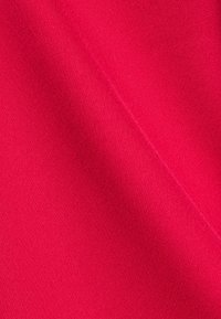 Tessuto fucsia brillante con una superficie liscia e leggermente testurizzata, che mostra sottili variazioni di tonalità e profondità, evidenziando la sua ricchezza di colore.