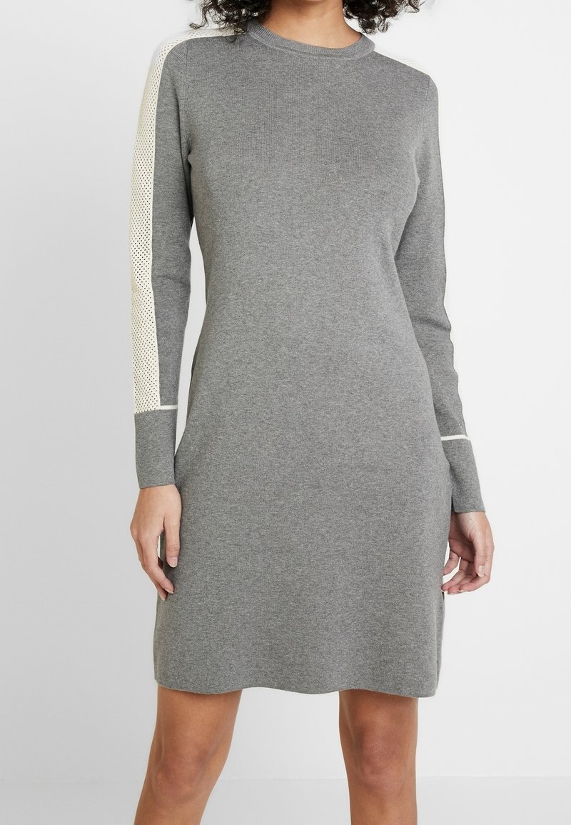 Abito a maglia grigio con maniche lunghe, scollatura rotonda e accenti testurizzati di un colore più chiaro sulle maniche. Silhouette semplice e aderente.