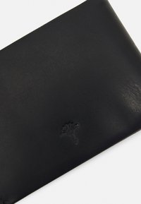 Black leather wallet with a soft texture, featuring a debossed logo of a palm tree. Compact rectangular shape, minimalistic design.