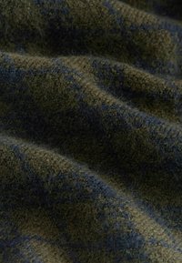 Ulltyg med en mjuk, texturerad yta; mörk olivgrön med marinblå horisontella ränder som ger ett varmt intryck.