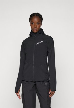 Black TERREX jacket with a zip front, hood, and long sleeves. Features textured fabric and a geometric design on the chest.