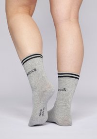 Graue Knöchelsocken mit schwarzen Streifen am oberen Rand, die eine gestrickte Textur aufweisen und den Markennamen "SNOCKS" an den Seiten aufgedruckt haben.