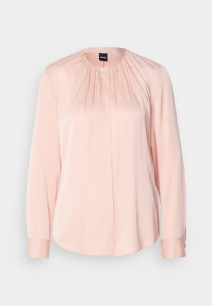 Light pink blouse featuring a pleated design, long sleeves, a round neckline, and button cuffs. Made from a smooth, soft fabric.