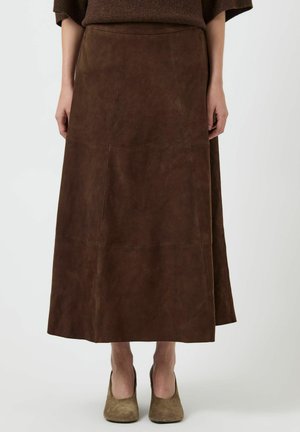Jupon maxi en suédine marron avec coutures verticales, présentant une coupe décontractée et une texture lisse, associé à des talons en suédine marron.