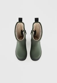 Bottes étanches vertes avec un matériau extérieur lisse, doublure en peluche et semelles en caoutchouc noires. Comprend une fermeture éclair de chaque côté et des anses.